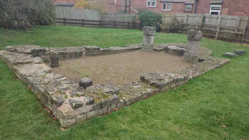 In the middle of a typical English suburb, the ruins of an old Roman temple. There's not much left — just a stone-brick border and a few altars, the naos being filled in with gravel.