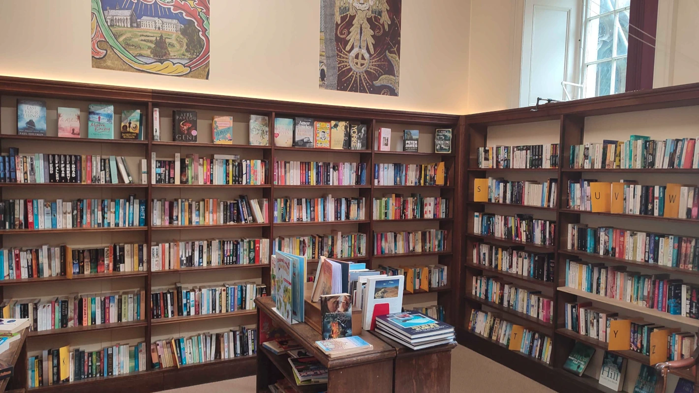 A wee bookshop with dark wooden shelves and religious posters