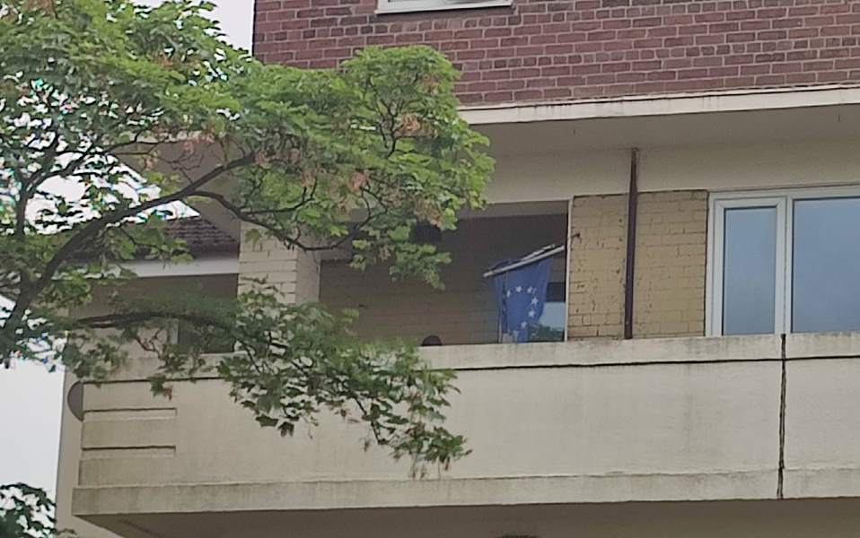 A worn European Union flag hangs over a balcony.