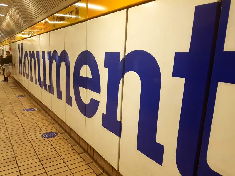 Het reuzenetiket van metrostation Monument strekt zich uit naar de achtergrond.