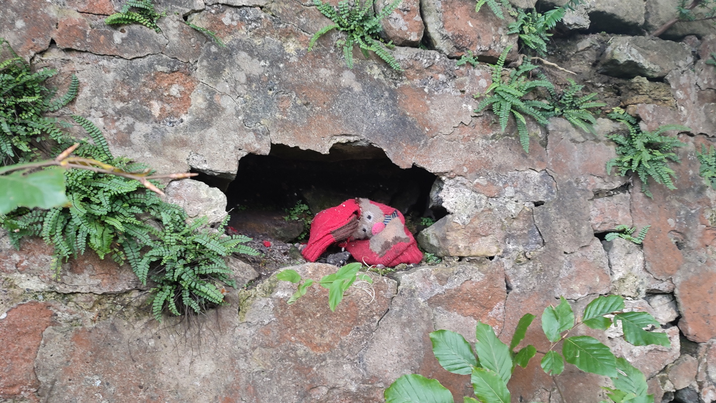 A reindeer stocking covered in dirt languishes inside a hole in the wall