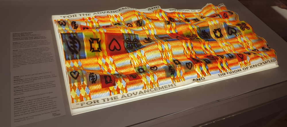 A lit up colourful glass tapestry marked with traditional Ghanaian patterns