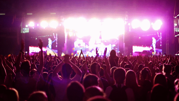 A packed concert bathed in purple light.