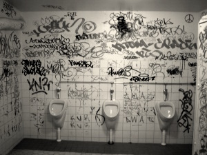 A public toilet covered in graffiti from floor to ceiling.